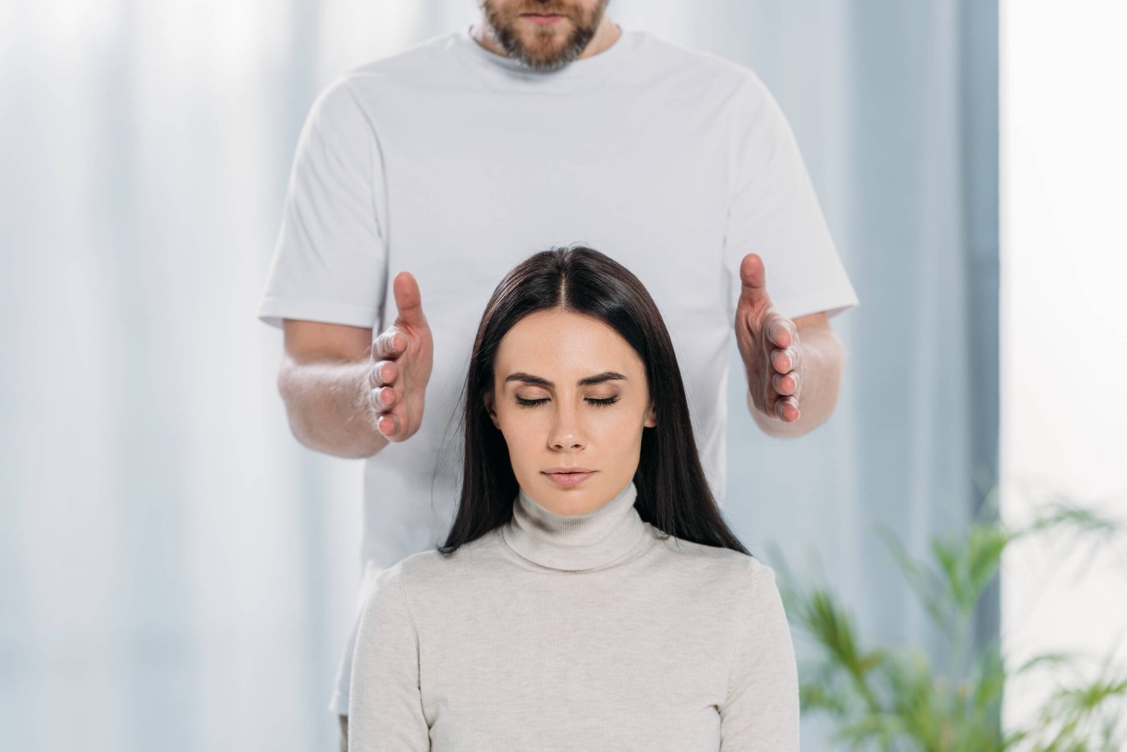 cropped shot of bearded healer doing reiki therapy session to young woman with closed eyes cropped shot of bearded healer doing reiki therapy session to young woman with closed eyes